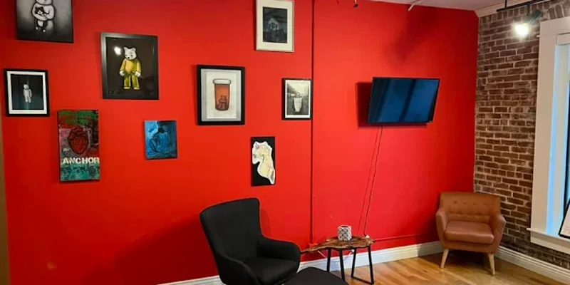 Lounge with red accent wall, art, and modern chairs