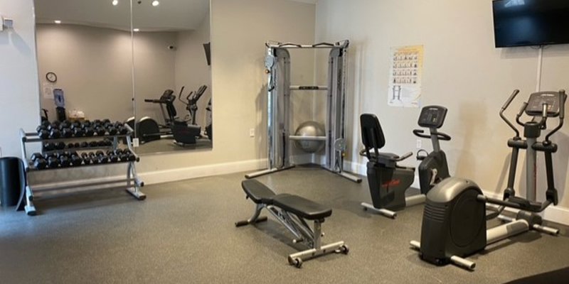 A fitness room with gym equipment, weights, and mirrors.