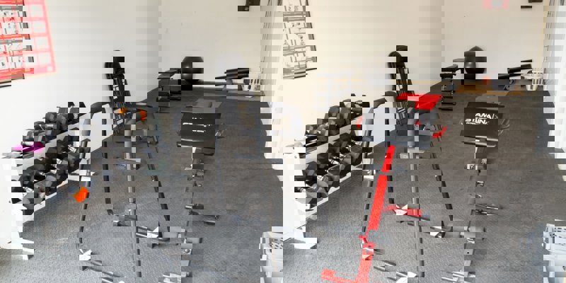 A small gym with weights, exercise equipment, and mats.