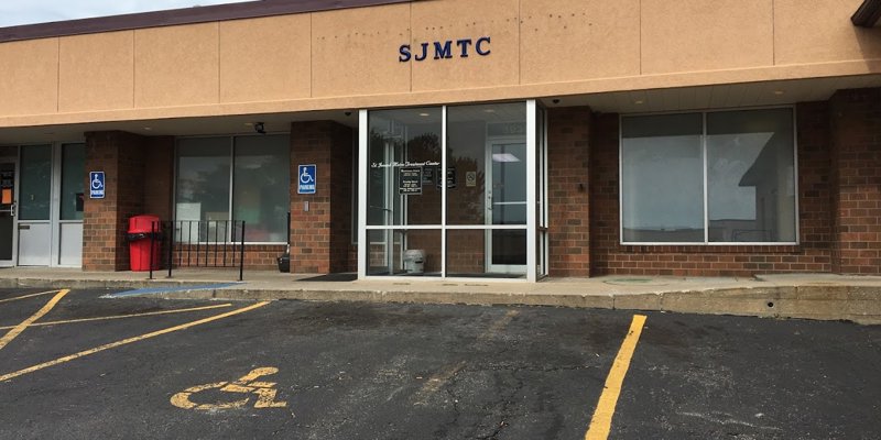 Exterior of SJMTC with glass doors, brick walls, and handicap parking.