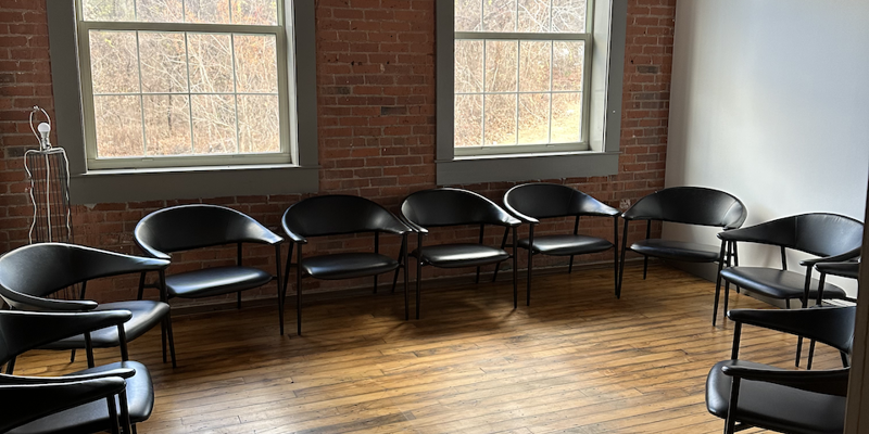 Group therapy room with black chairs arranged in a circle