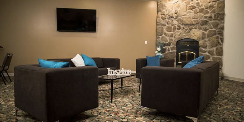 Lounge area with couches, a stone fireplace, and a TV.