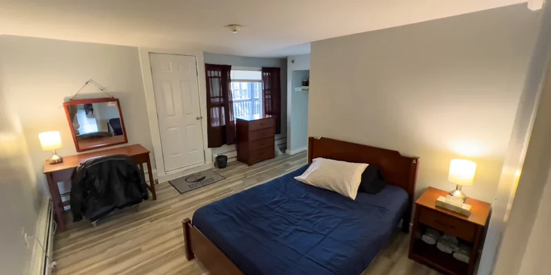 Bedroom with a single bed, nightstands, and wood flooring