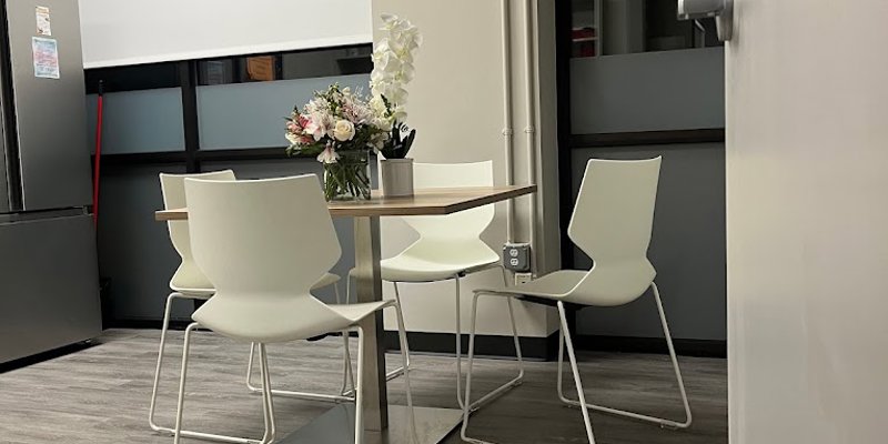 A small dining area with a table and white chairs.