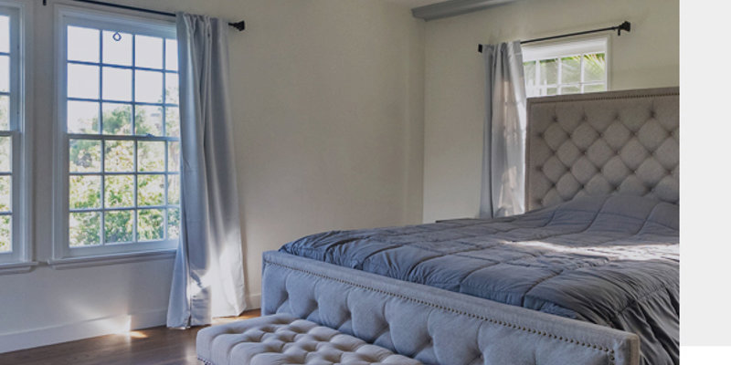 Private bedroom with a bed and ottoman.