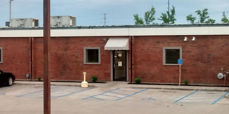 Single-story brick building with a white awning and accessible parking spaces.