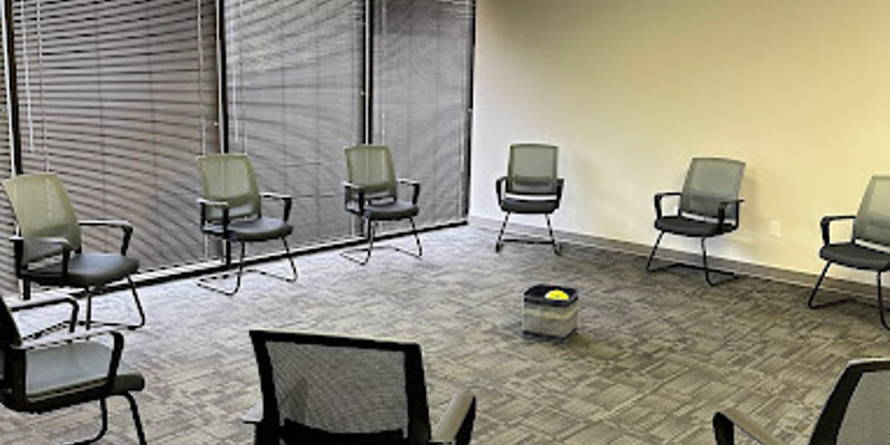 A group therapy room with chairs arranged in a circle near large windows.