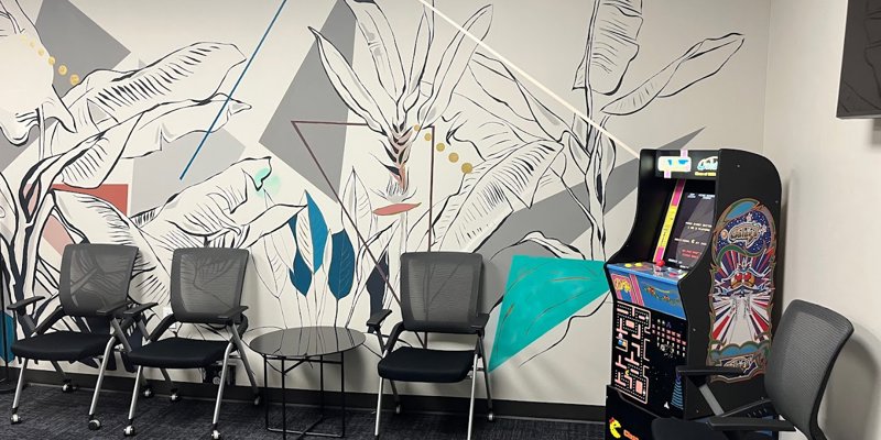 A lounge with modern art, chairs, and an arcade game.