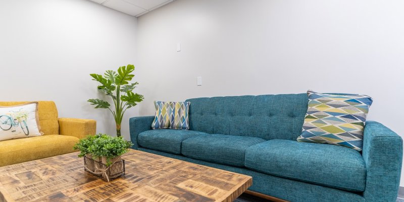 Cozy lounge with a blue couch, yellow armchair, and wooden coffee table.