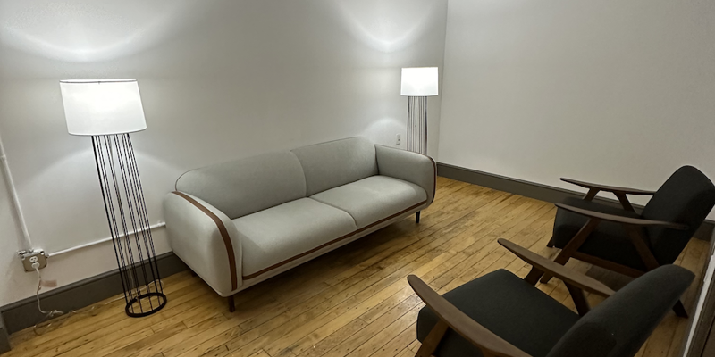 Minimalist therapy room with sofa, chairs, and standing lamps