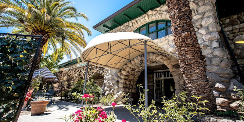 A rehab facility entrance with a canopy, flowers, and stone archways.