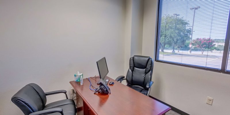 A private office with a desk, two chairs, and a window view