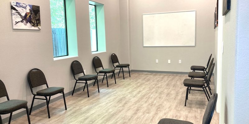 A therapy room with chairs arranged in a circle and a whiteboard on the wall.