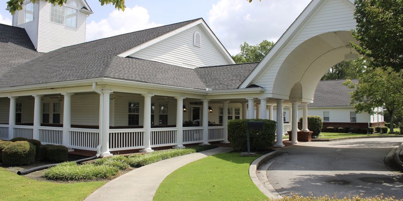 White-pillared building with circular driveway and lawn