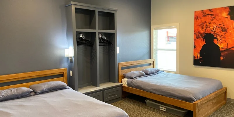Two twin beds with open closets and wall art
