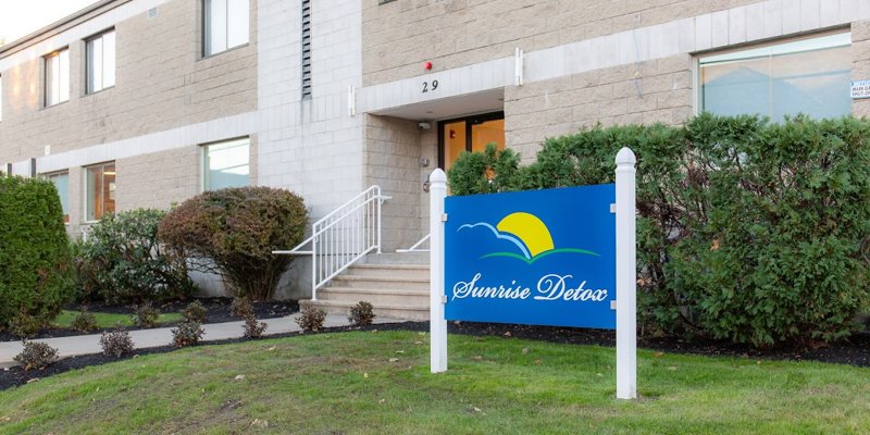 Entrance sign with green lawn and walkway leading to facility.