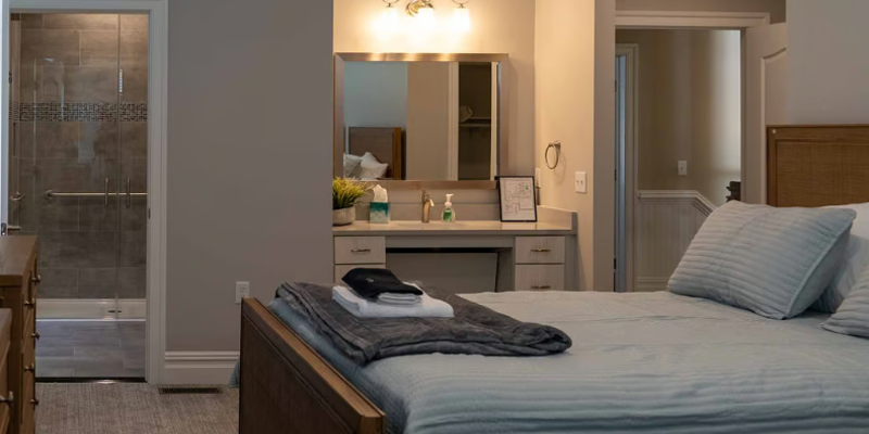 Modern bedroom with gray bedding, vanity, and adjacent bathroom