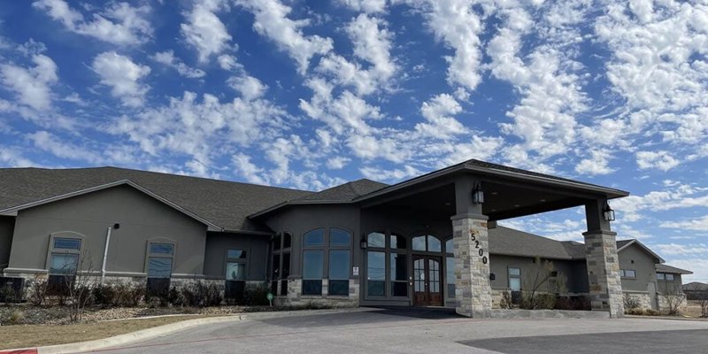 Facility exterior with large windows and accessible parking.