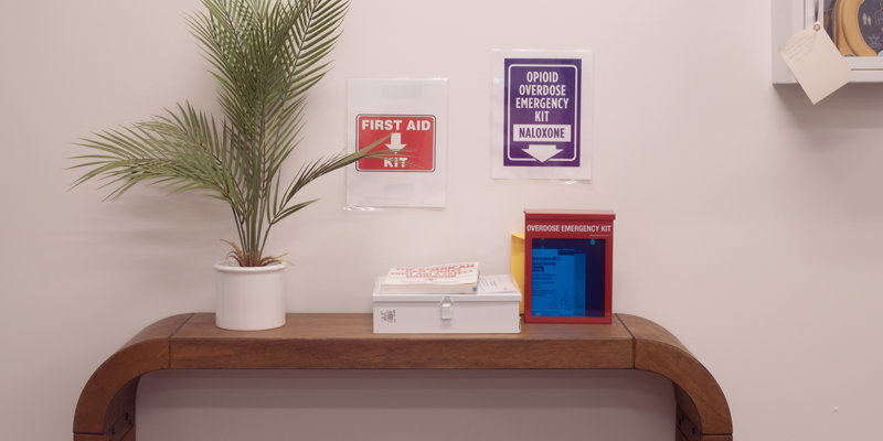 First aid and overdose kits with signs on a wood table