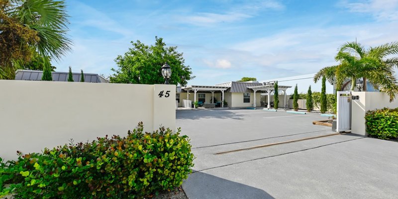 xterior view with white wall labeled 45, gated entry, and greenery.
