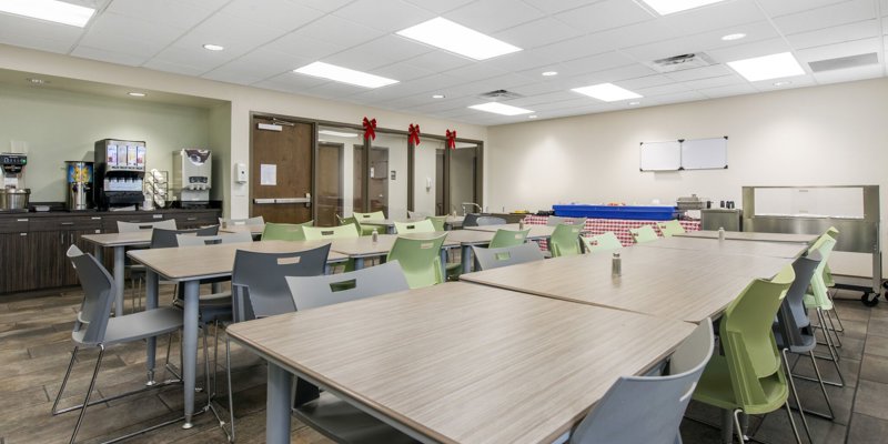 Rehab dining area with modern tables, chairs, and a food service counter.