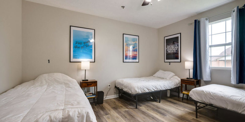 Shared bedroom with three beds, framed artwork, and natural lighting.