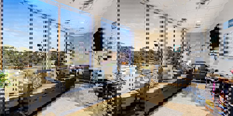 Bright lounge area with black couches, TV, and board games