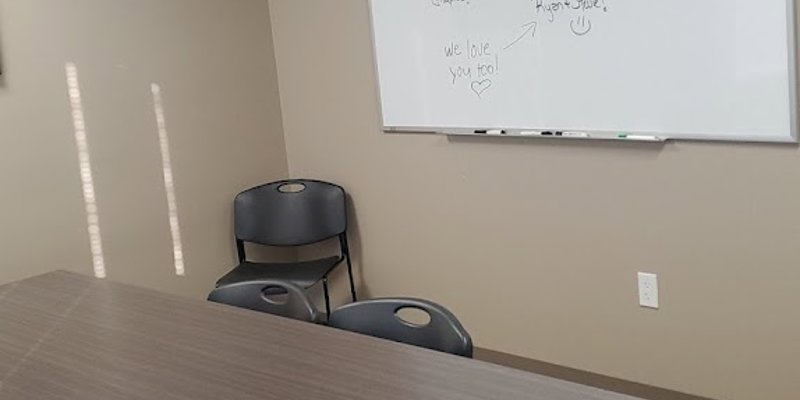 Therapy room with a table, chairs, and a whiteboard.