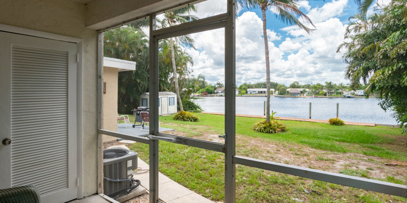 Screened patio overlooking water and green lawn