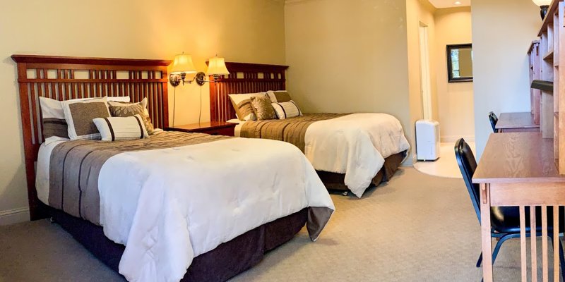 Cozy bedroom with two beds, warm lighting, and study desks
