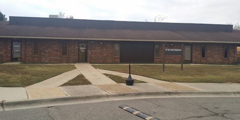 Exterior of facility with accessible pathways and signage on lawn post.