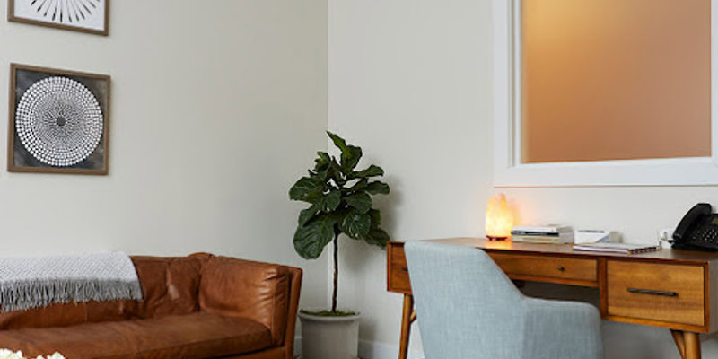 Therapy room with a couch and a desk.