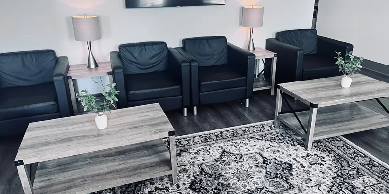 Lounge-style sitting area with black armchairs, coffee tables, and a patterned rug
